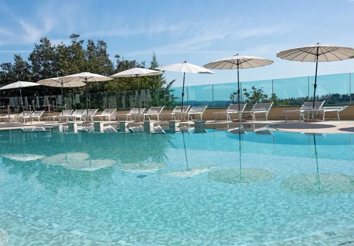 Piscina con lettini e ombrelloni, riflessi sull'acqua cristallina. Un angolo di relax a **Abbadia San Salvatore terme**.