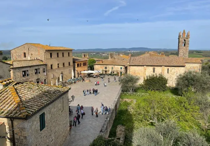 Piazza di Monteriggioni, un borgo medievale con case in pietra e un campanile. Ecco cosa vedere: un luogo incantevole da esplorare.