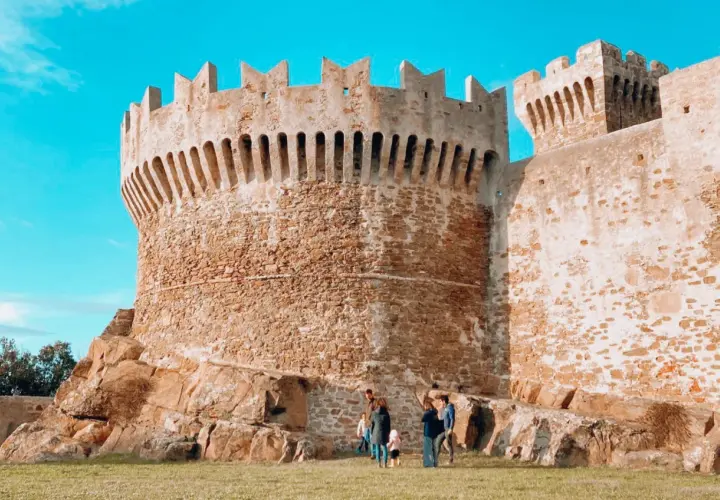 Antica fortezza in pietra, uno dei borghi vicino Livorno, con una famiglia che passeggia sull'erba.