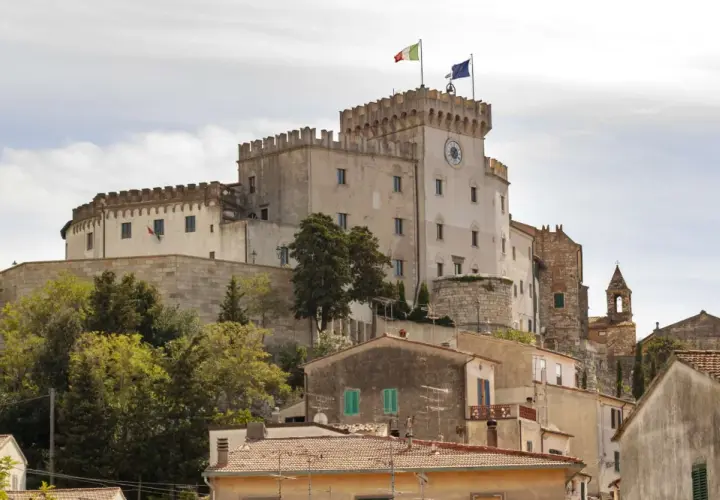 Castello Pasquini domina il paesaggio di Rosignano Marittimo, con le sue torri merlate e le bandiere che sventolano al vento.