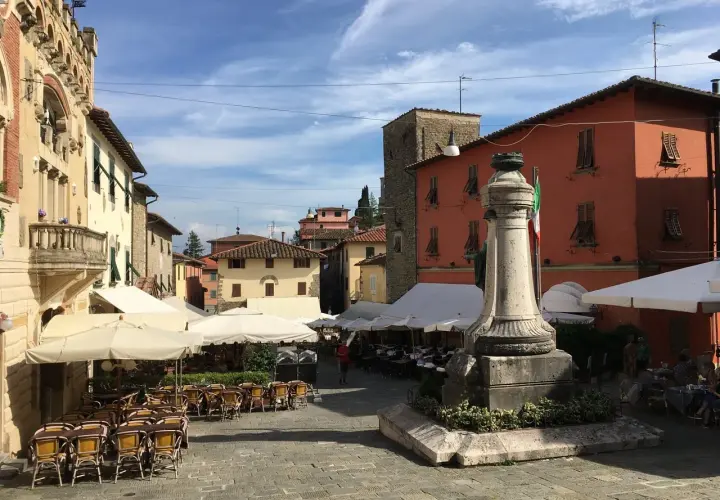 Piazza di Montecatini Alto, con tavolini all'aperto e un monumento. Un assaggio di cosa vedere a Montecatini Alto.