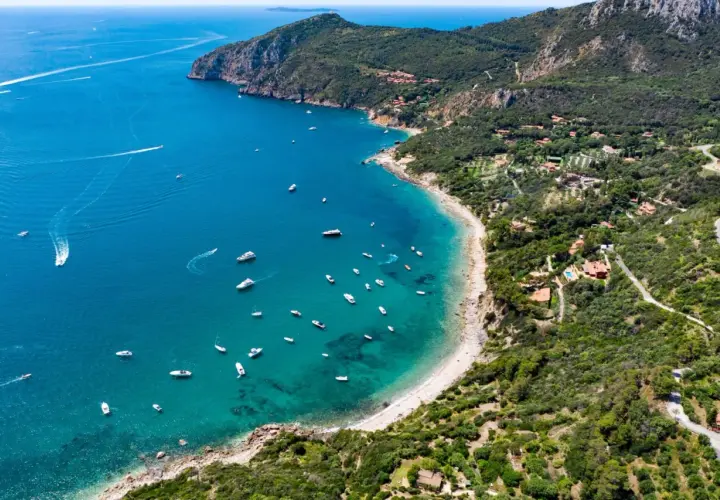 Baia con acque cristalline e numerose barche al largo di Porto Santo Stefano.