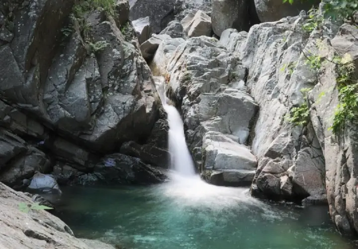 Cascate naturali in Lunigiana, con acqua cristallina che scende tra rocce grigie e vegetazione rigogliosa. Un angolo di paradiso selvaggio.