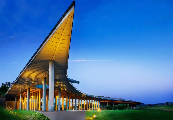 La tenuta ammiraglia Frescobaldi, con la sua architettura moderna illuminata, si staglia contro il cielo serale. Le recensioni lodano questo luogo.