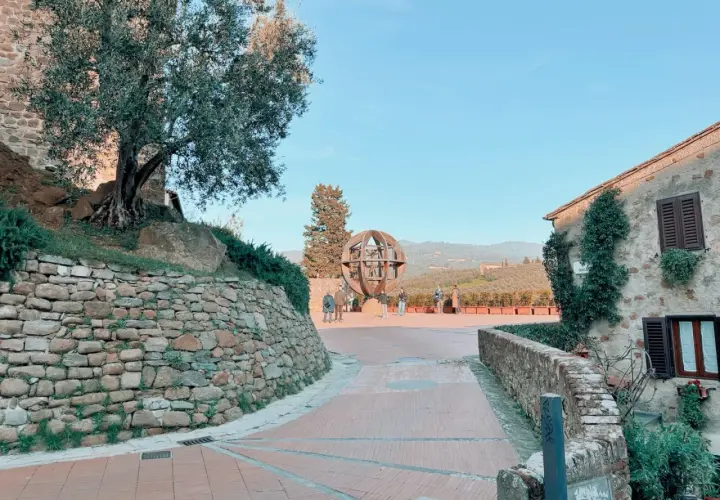 Vinci cosa vedere: un'installazione artistica a forma di globo, un ulivo secolare e case in pietra con vista sulle colline toscane.