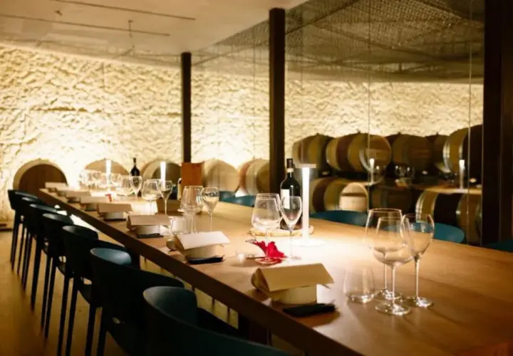Tavola apparecchiata in una cantina dei vini, con botti sullo sfondo.