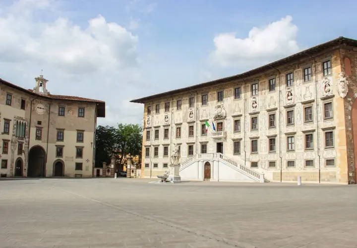 La **piazza dei Cavalieri** a Pisa, con i suoi palazzi storici e la scalinata monumentale, sotto un cielo nuvoloso.