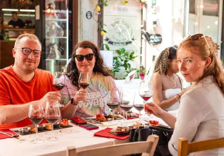 Amici brindano a una degustazione vini a Pisa, assaporando sapori toscani con un bicchiere di rosso.