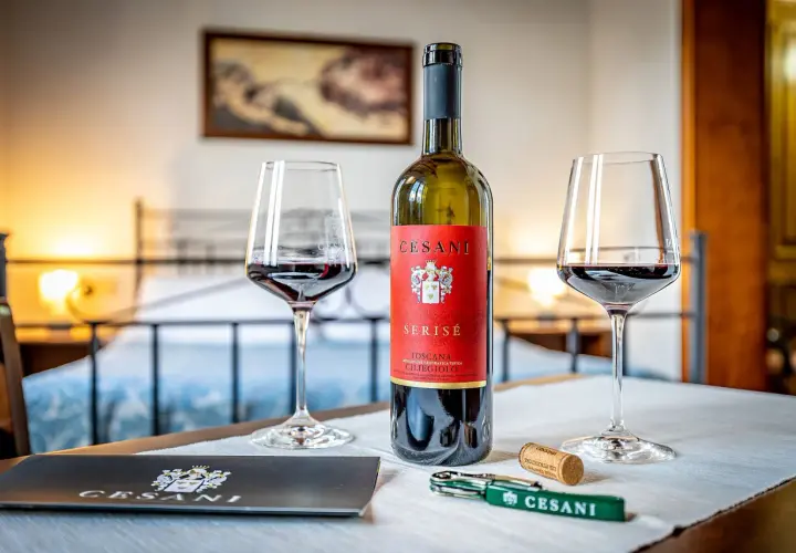 Un calice di vino rosso Cesani, una bottiglia di Serisé Ciliegiolo e un cavatappi, pronti per una degustazione alla Cesani winery.