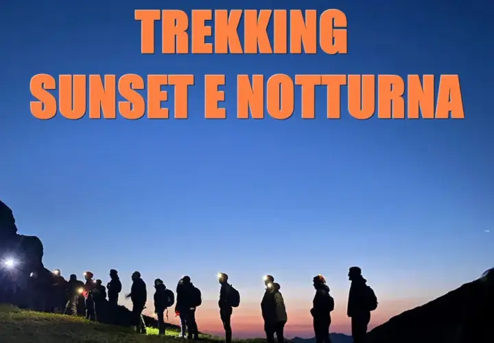 Gruppo di escursionisti al tramonto e di notte al passo dell'Abetone, con luci frontali accese.