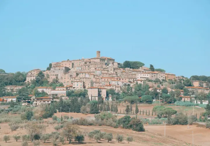 Panoramica di Casale Marittimo, un borgo medievale toscano arroccato su una collina, con case in pietra e tetti rossi, circondato da ulivi e cipressi.