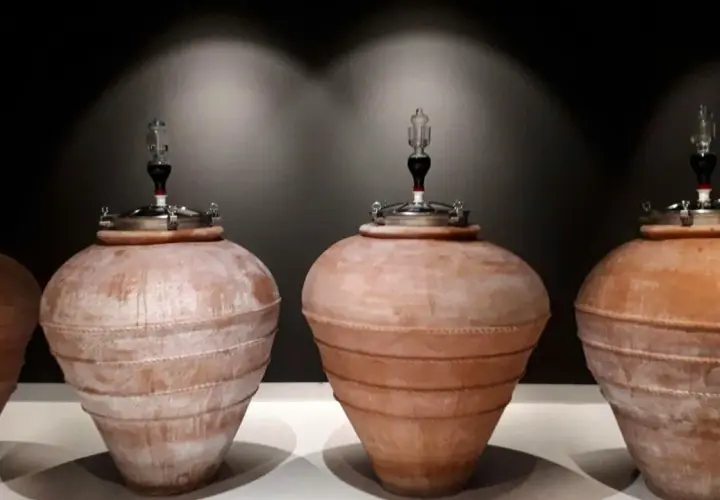 Quattro anfore in terracotta, con tappi metallici e gorgogliatori, pronte per la fermentazione del vino.
