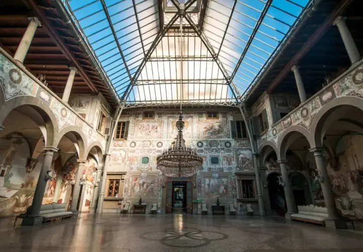 Interno di ville medicee visitabili con affreschi, un grande lampadario e tetto in vetro.