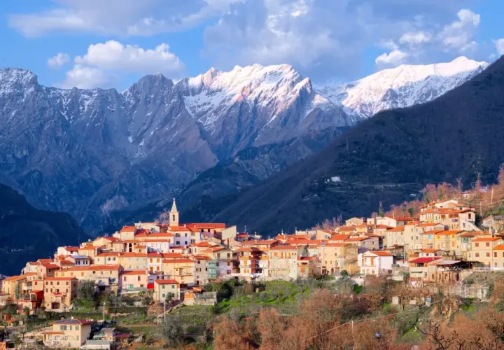 Borgo pittoresco alle pendici delle Alpi Apuane, con case dai tetti rossi e montagne innevate sullo sfondo. Un luogo incantevole da scoprire.