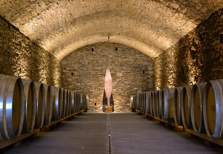 Cantine in pietra con botti di legno, un'installazione artistica al centro. Perfetto per una visita cantine Chianti.