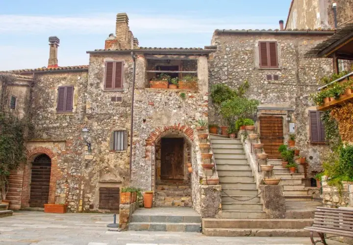 Un pittoresco borgo toscano con case in pietra, scale in terracotta e piante rigogliose.