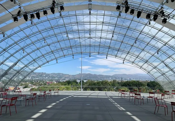 Spazi all'aperto del museo de la academia, con sedie rosse disposte e vista sulle colline di Los Angeles sotto una struttura a volta in vetro.