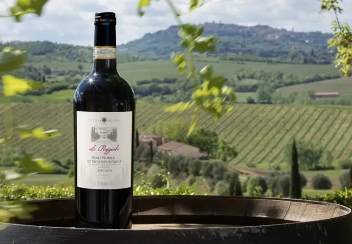 Bottiglia di Vino Nobile di Montepulciano su un barile, con sullo sfondo le dolci colline toscane e i loro vigneti.