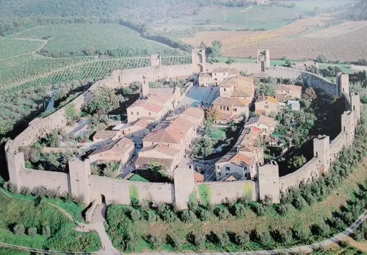 Vista aerea di Monteriggioni, un borgo medievale fortificato in Toscana, con le sue mura intatte e le torri che si stagliano sul paesaggio collinare.