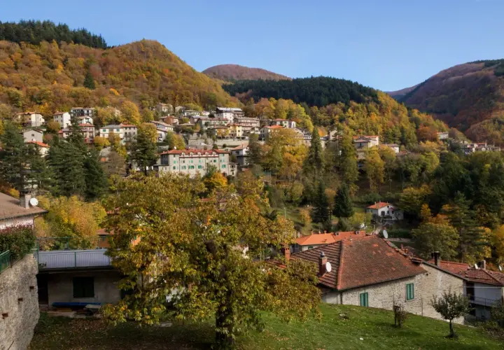 Case colorate e boschi autunnali abbracciano il borgo di Badia Prataglia, un incantevole paesaggio appenninico.