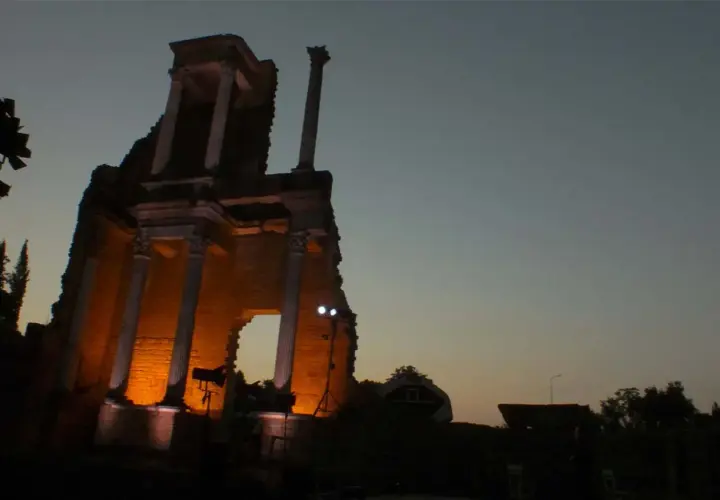 Il teatro romano di Volterra illuminato di sera, con le sue antiche colonne che emergono dall'ombra.