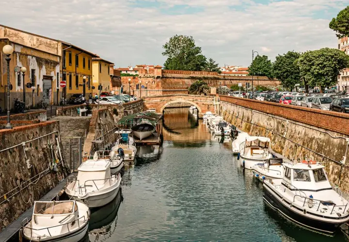 Canali di Livorno, un'ottima idea per cosa vedere in 2 giorni: barche ormeggiate lungo i muri di mattoni, un ponte ad arco e palazzi storici.