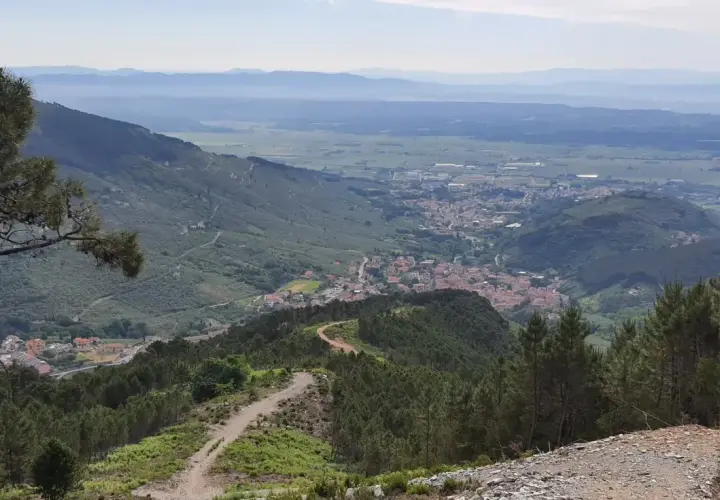 Panoramica mozzafiato con un sentiero tortuoso tra i pini, che conduce a un villaggio incastonato tra le colline. Buti cosa vedere in questo paesaggio incantevole.