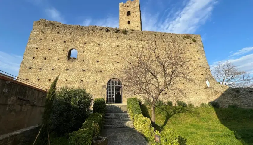 Rovine del castello di Larciano Pistoia, con torre, mura in pietra e un piccolo giardino curato.