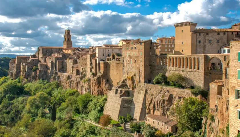 Un borgo arroccato su una rupe, con case in pietra e un campanile svettante, sembra una piccola Gerusalemme sotto un cielo azzurro e nuvoloso.