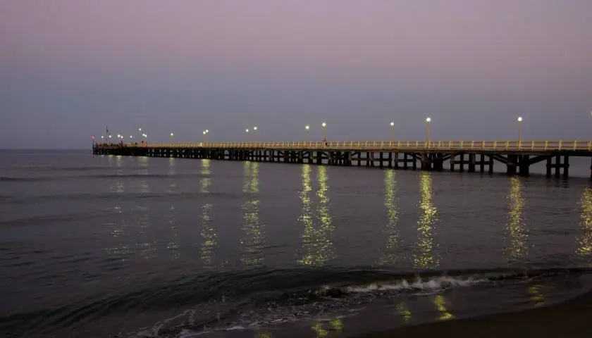 Il pontile di Forte dei Marmi illuminato al crepuscolo, con le luci che si specchiano sul mare calmo.