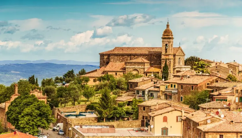 Panoramica di Montalcino, borgo medievale toscano con la sua imponente cattedrale e le case in pietra, immerso nel verde delle colline.