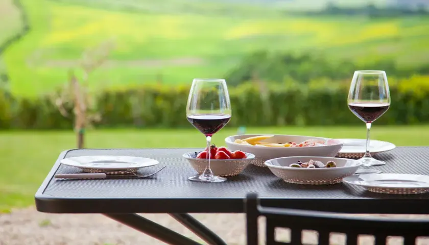Un bicchiere di vino rosso e stuzzichini su un tavolo con vista sui chianti vineyards.