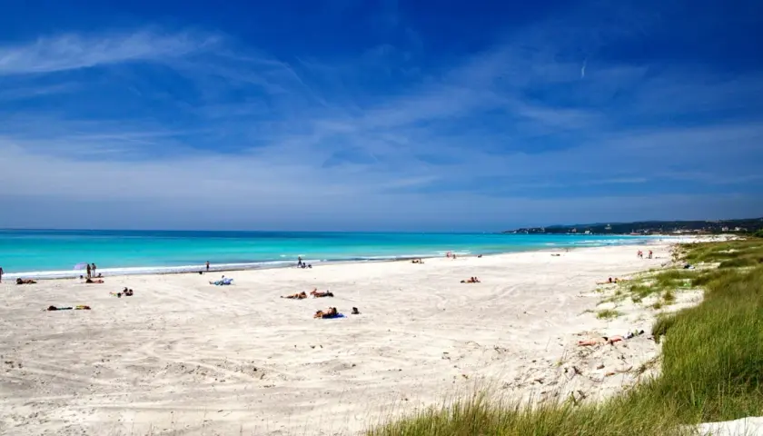 Vada Spiagge Bianche: sabbia chiara, mare turchese e cielo azzurro. Persone rilassate al sole su questa splendida costa.