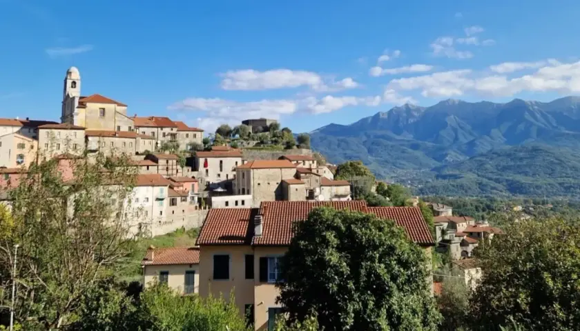 Panoramica di Mulazzo, borgo ligure con case in pietra e tetti rossi, dominato da un castello e con montagne sullo sfondo. Cosa vedere in questo incantevole paese.