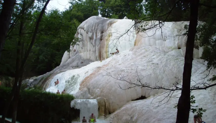 Cascate di travertino a Santa Fiora Terme, con persone che si rilassano nelle acque termali.