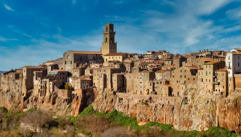 Il centro storico di Pitigliano, arroccato su una rupe tufacea, con le sue case antiche e la torre campanaria che domina il paesaggio.