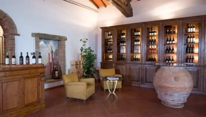 Interno accogliente della cantina Melini, con bottiglie di vino esposte su scaffali in legno e un'antica anfora.