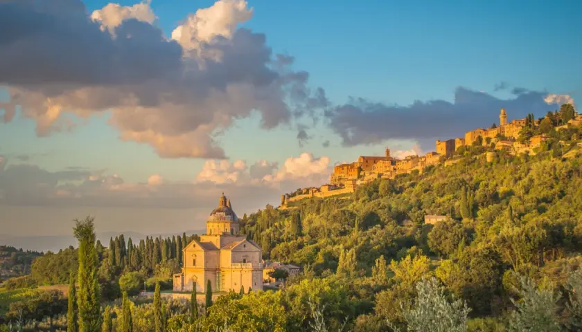 La chiesa rinascimentale e il borgo medievale, incastonati tra colline verdi, mostrano dove si trova Montepulciano al tramonto.