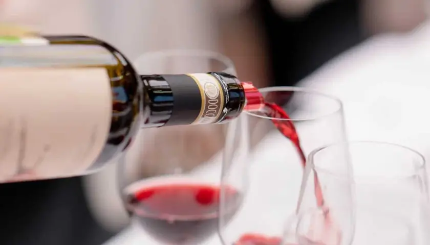 Versando vino rosso da una bottiglia in calici, un'esperienza dei migliori vini Chianti.