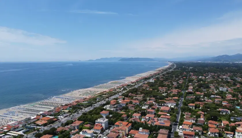 Vista aerea della costa toscana, dove si trova Forte dei Marmi, con spiagge attrezzate, mare blu e un fitto tessuto urbano.