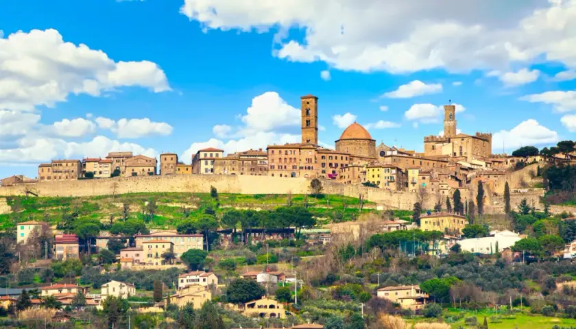 Panoramica di Volterra, con torri medievali e case in pietra su una collina verde. Molte cose da fare a Volterra, tra cui esplorare il centro storico.