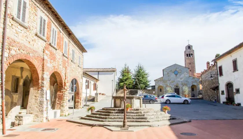 Piazza di Civitella Val di Chiana con pozzo antico, chiesa romanica e case in pietra.