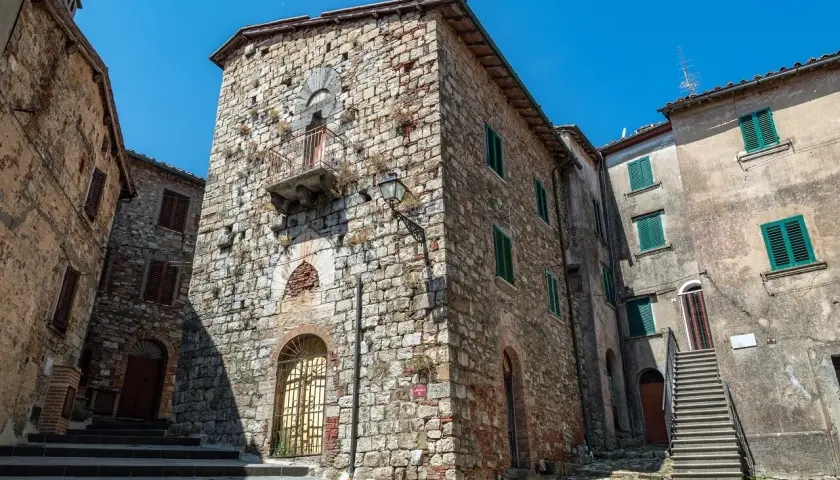 Antiche case in pietra a Montieri, cosa vedere: un vicolo con scale, balcone e finestre verdi.