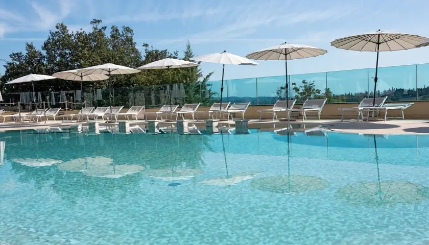 Piscina con lettini e ombrelloni, riflessi sull'acqua cristallina. Un angolo di relax a **Abbadia San Salvatore terme**.