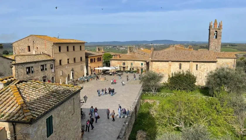 Piazza di Monteriggioni, un borgo medievale con case in pietra e un campanile. Ecco cosa vedere: un luogo incantevole da esplorare.