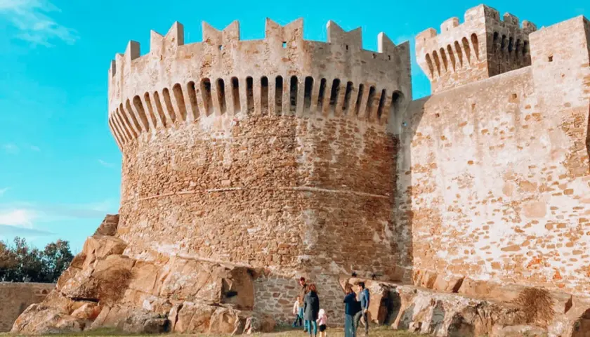 Antica fortezza in pietra, uno dei borghi vicino Livorno, con una famiglia che passeggia sull'erba.