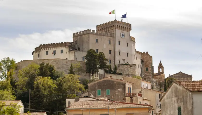Castello Pasquini domina il paesaggio di Rosignano Marittimo, con le sue torri merlate e le bandiere che sventolano al vento.