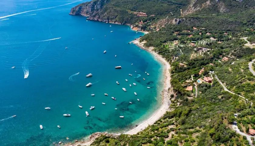 Baia con acque cristalline e numerose barche al largo di Porto Santo Stefano.