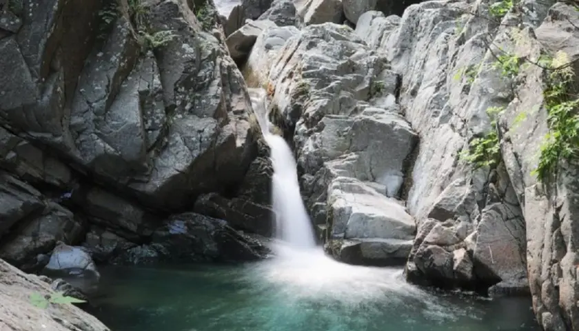 Cascate naturali in Lunigiana, con acqua cristallina che scende tra rocce grigie e vegetazione rigogliosa. Un angolo di paradiso selvaggio.