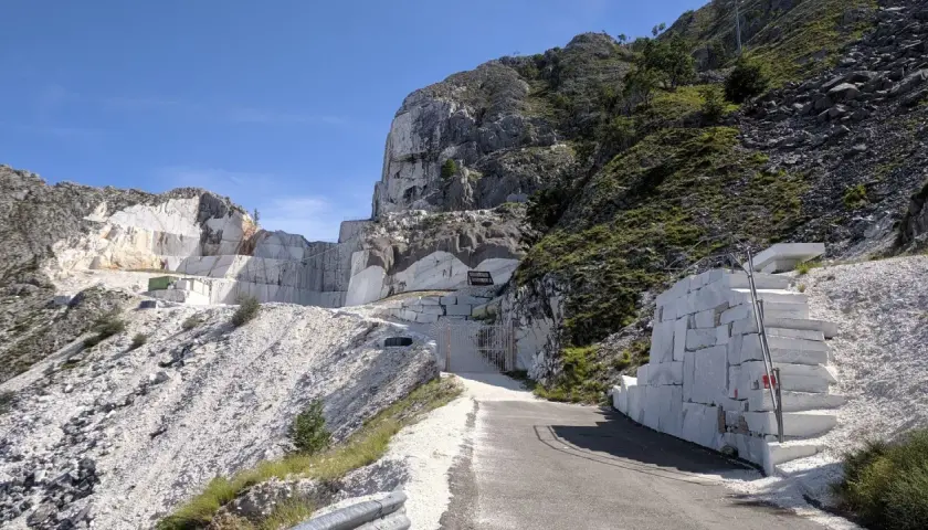 Un imponente passo del vestito di marmo bianco si erge su un fianco della montagna, con blocchi grezzi e una scala scavata nella roccia.